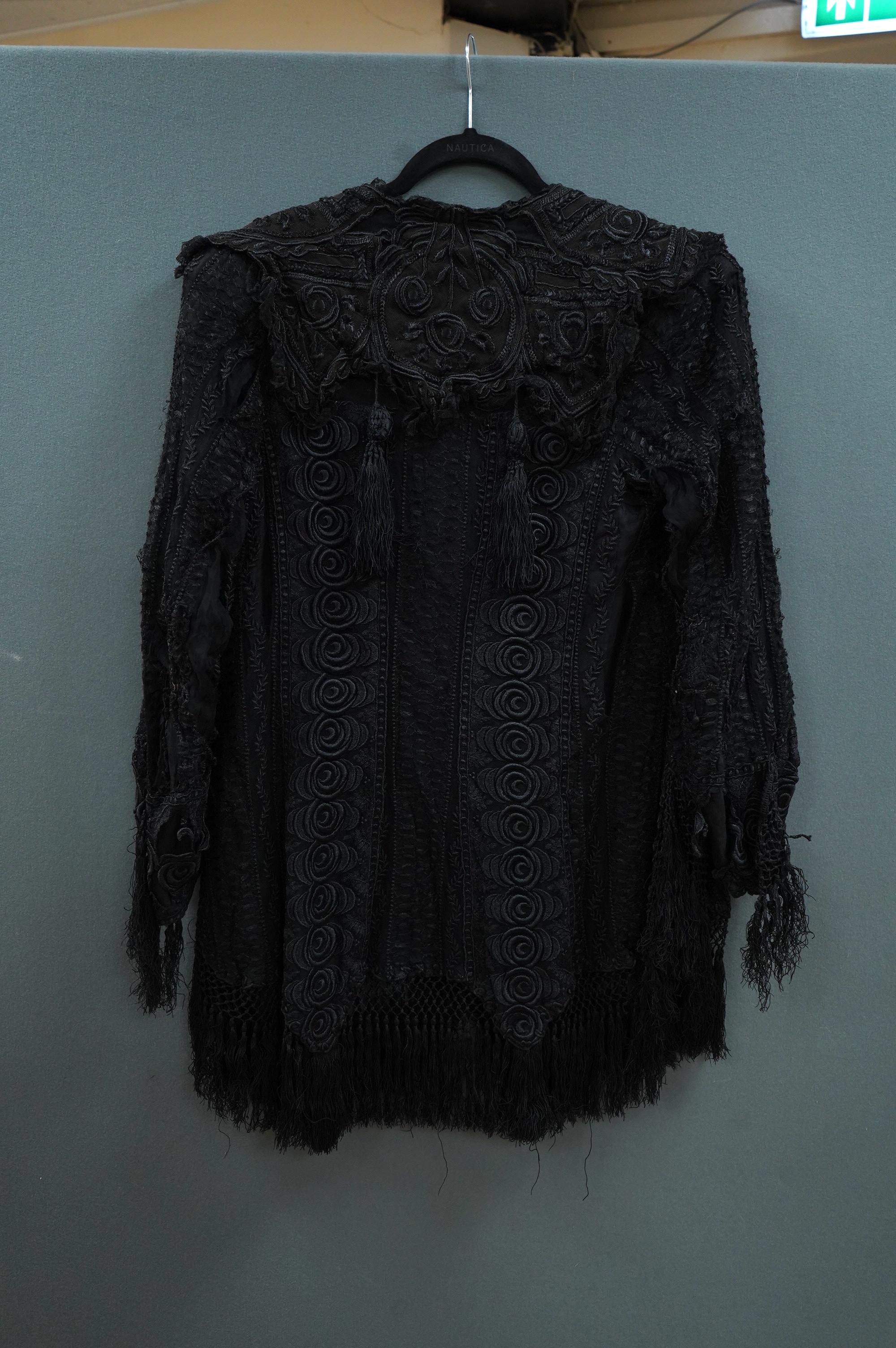 An Edwardian black chiffon and lace evening jacket with tassel decoration to the front and back, edged with tasselled fringing to the edge of sleeves and bottom, 85cm long from nape of neck at the back to bottom of tasse